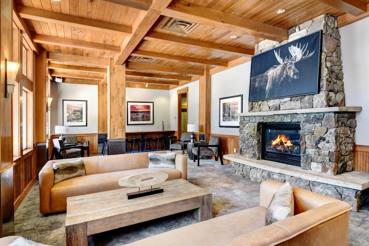 A welcoming lobby interior with a grand stone fireplace, wooden beams, plush sofas, and charming artwork. The fireside setting invites guests to socialize, relax, or enjoy a cozy evening after outdoor activities.