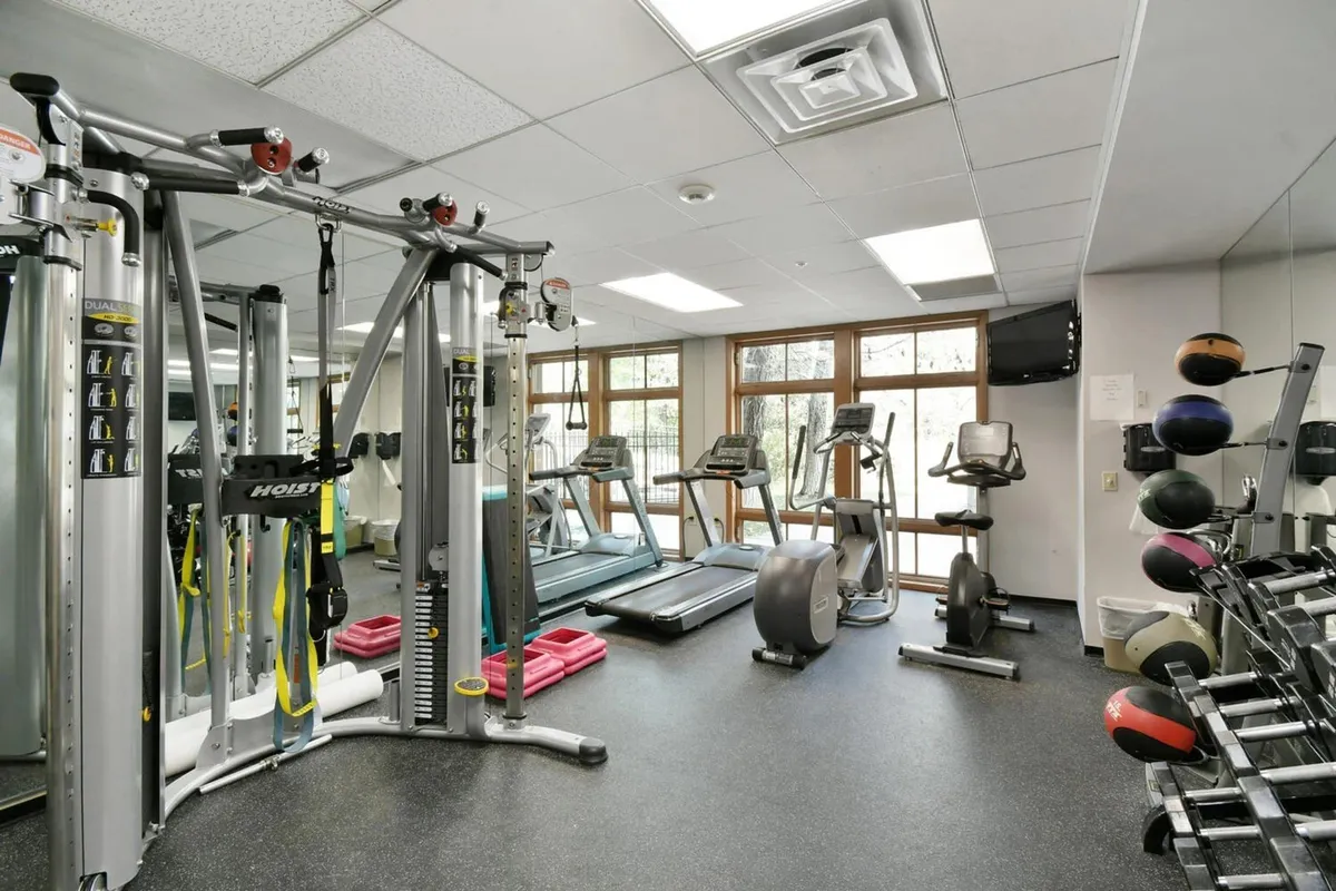 A bright, modern gym interior featuring multi-station equipment, treadmills, and large windows providing natural light. The space feels energetic and inviting, perfect for both solo workouts and group classes.